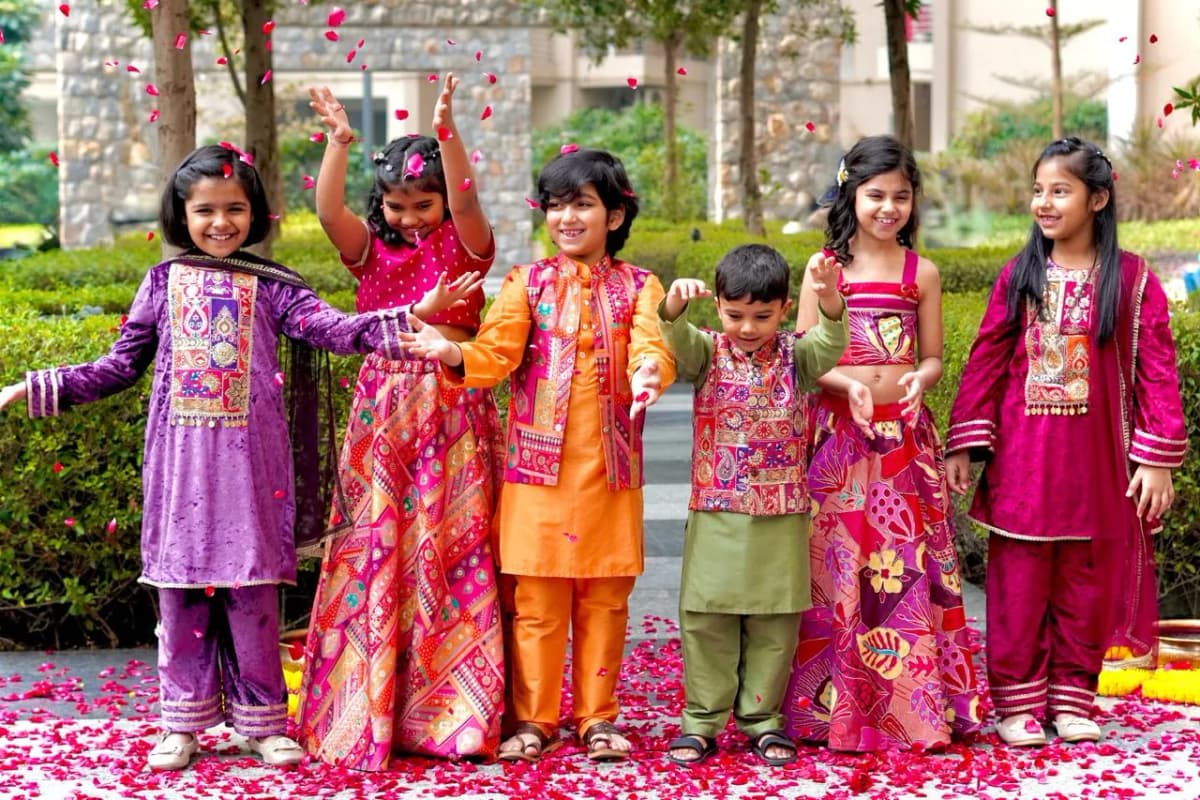 Six children in colourful festive outfits standing in a garden