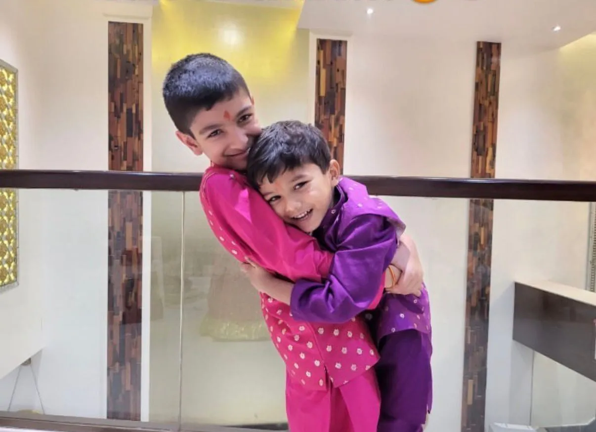 Two brothers in pink and purple kurtas hugging